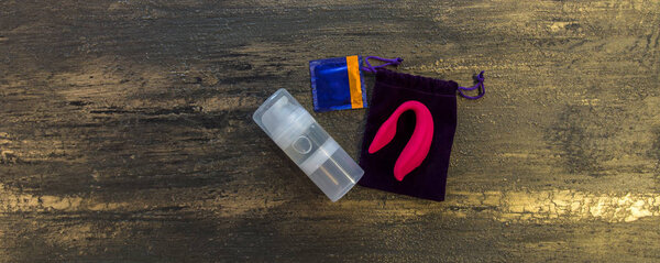 Intimate lubrication condom and dildo on the fabric background