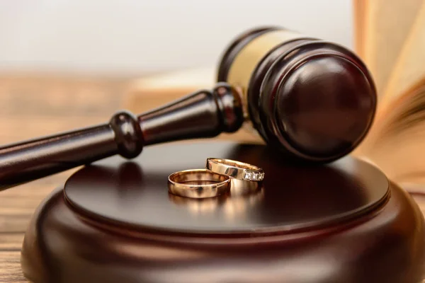 Law and Justice. Judge gavel and wedding rings on wooden background