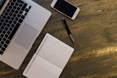 Metin kopyalama yeri olan eski bronz arka plan üzerinde tablo ya da dizüstü bilgisayar, boş defter, kalem ve akıllı telefon Danışma üstten görünüm.