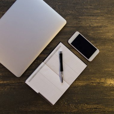 Metin kopyalama yeri olan eski bronz arka plan üzerinde tablo ya da dizüstü bilgisayar, boş defter, kalem ve akıllı telefon Danışma üstten görünüm.