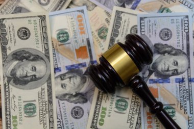 judge gavel lie on background from one hundred dollar bills on wooden background clipart