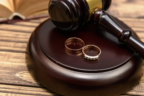 Law and Justice. Judge gavel and wedding rings on wooden background