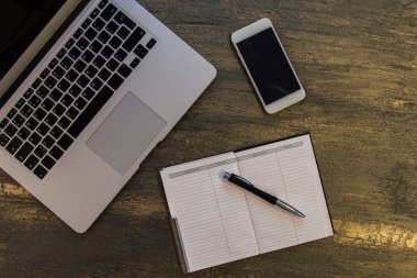 Metin kopyalama yeri olan eski bronz arka plan üzerinde tablo ya da dizüstü bilgisayar, boş defter, kalem ve akıllı telefon Danışma üstten görünüm.