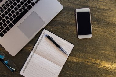 Metin kopyalama yeri olan eski bronz arka plan üzerinde tablo ya da dizüstü bilgisayar, boş defter, kalem, gözlük ve akıllı telefon Danışma üstten görünüm.
