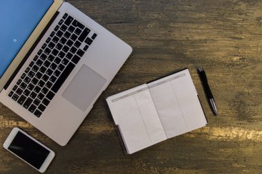 Metin kopyalama yeri olan eski bronz arka plan üzerinde tablo ya da dizüstü bilgisayar, boş defter, kalem ve akıllı telefon Danışma üstten görünüm.