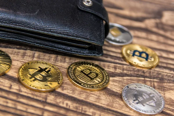 stock image  bitcoins, litecoin and ethereum in black leather wallet on old wooden table