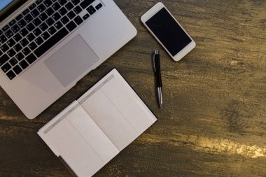 Metin kopyalama yeri olan eski bronz arka plan üzerinde tablo ya da dizüstü bilgisayar, boş defter, kalem ve akıllı telefon Danışma üstten görünüm.