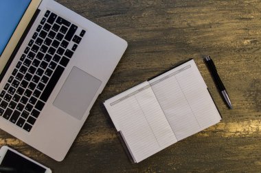 Metin kopyalama yeri olan eski bronz arka plan üzerinde tablo ya da dizüstü bilgisayar, boş defter, kalem ve akıllı telefon Danışma üstten görünüm.