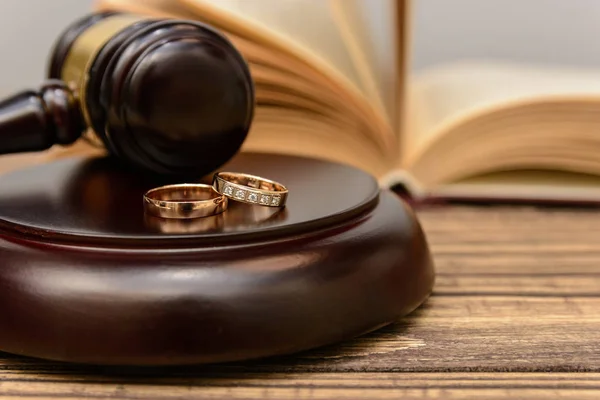 Law and Justice. Judge gavel and wedding rings on wooden background