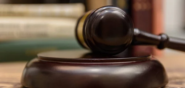 judge gavel beside pile of books on wooden background