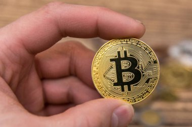 Adamın parmakları eski ahşap arka plan üzerinde tutan bitcoin