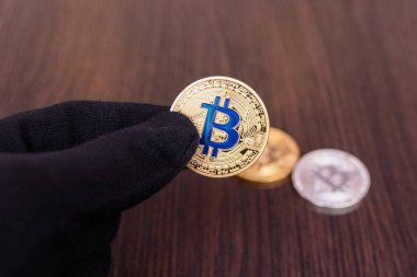 siyah eldiven elinde altın bitcoin