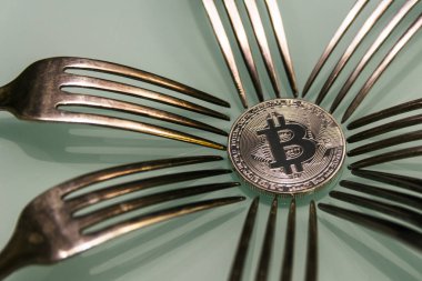  onun etrafında gümüş çatal ile cam tabloda altın bitcoin