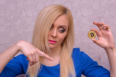 mavi elbiseli güzel bir sarışın kızın elinde altın bitcoin