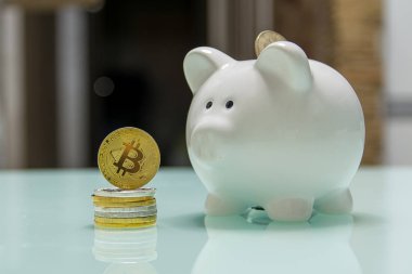 Seramik kumbara yanında sikke yığını üzerinde durabilen altın bitcoin 