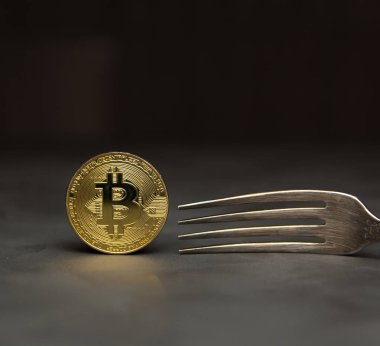  Gümüş çatal ile koyu arka plan üzerinde altın bitcoin