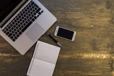 Metin kopyalama yeri olan eski bronz arka plan üzerinde tablo ya da dizüstü bilgisayar, boş defter, kalem ve akıllı telefon Danışma üstten görünüm.