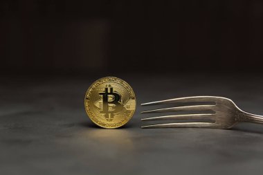  Gümüş çatal ile koyu arka plan üzerinde altın bitcoin