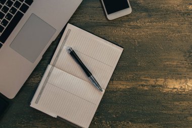 Metin kopyalama yeri olan eski bronz arka plan üzerinde tablo ya da dizüstü bilgisayar, boş defter, kalem ve akıllı telefon Danışma üstten görünüm.