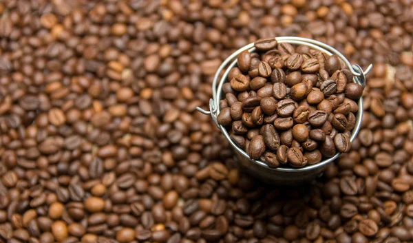 Kahve çekirdekleri arka planda oyuncak metal kova