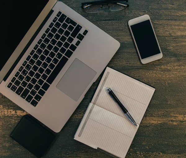 Metin kopyalama yeri olan eski bronz arka plan üzerinde tablo ya da dizüstü bilgisayar, boş defter, kalem ve akıllı telefon Danışma üstten görünüm.