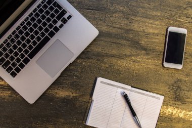 Metin kopyalama yeri olan eski bronz arka plan üzerinde tablo ya da dizüstü bilgisayar, boş defter, kalem ve akıllı telefon Danışma üstten görünüm.