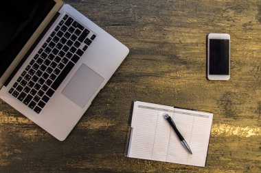 Metin kopyalama yeri olan eski bronz arka plan üzerinde tablo ya da dizüstü bilgisayar, boş defter, kalem ve akıllı telefon Danışma üstten görünüm.