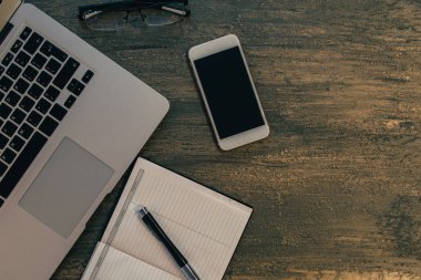 Metin kopyalama yeri olan eski bronz arka plan üzerinde tablo ya da dizüstü bilgisayar, boş defter, kalem ve akıllı telefon Danışma üstten görünüm.