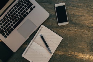 Metin kopyalama yeri olan eski bronz arka plan üzerinde tablo ya da dizüstü bilgisayar, boş defter, kalem ve akıllı telefon Danışma üstten görünüm.