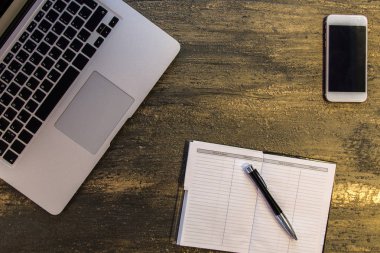 Metin kopyalama yeri olan eski bronz arka plan üzerinde tablo ya da dizüstü bilgisayar, boş defter, kalem ve akıllı telefon Danışma üstten görünüm.