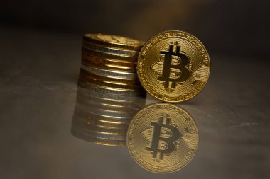  yansıtıcı yüzeyde altın bitcoin ve sikke yığını