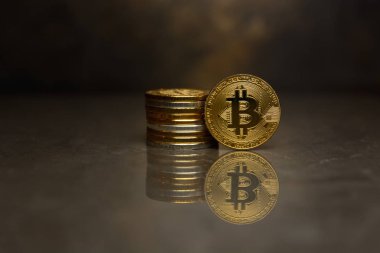  yansıtıcı yüzeyde altın bitcoin ve sikke yığını