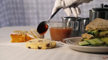 Traditional English tea with jam scone and cucumber sandwiches medium 4k shot selective focus