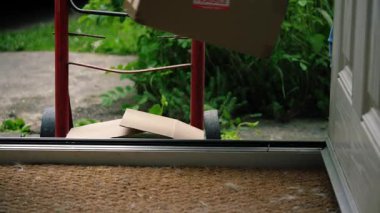 Delivery of cardboard boxes and trolley cart outside of home front door medium zoom shot selective focus