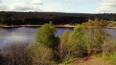 Tepe İlçesi Ulusal Parkı 'ndaki ağaçlar ve tarlalar çevresindeki göl mavi gökyüzü geniş 4k hava aracı seçici odak noktası