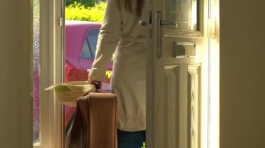 Woman with suitcase waiting at house front door medium 4k shot selective focus 