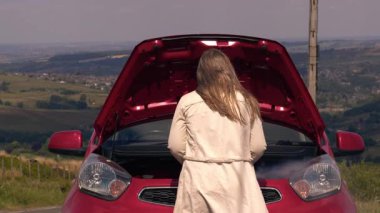 Motordan dumanlı, bozuk arabası olan bir kadın orta boy zum çekimi yapıyor. Seçici odaklanma.