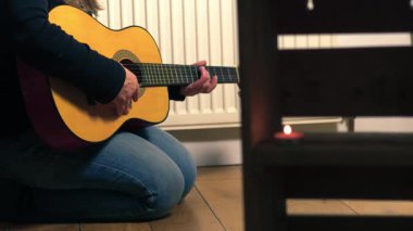Mumlu bir odada gitar çalan kadın seçici odaklanma görüntüsü verdi