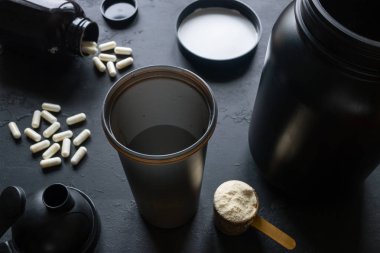 Shaker, protein, kreatin ve diğer spor takviyeleri üzerinde siyah bir arka plan