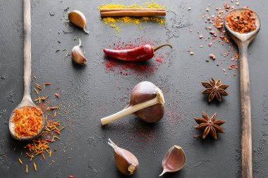 çeşitli baharatlar ve otlar siyah bir zemin üzerine tahta kaşıklar