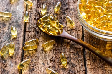 tahta kaşıkla ahşap arka plan üzerinde balık yağı kapsülleri