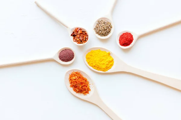 spoons with different spices on a white background