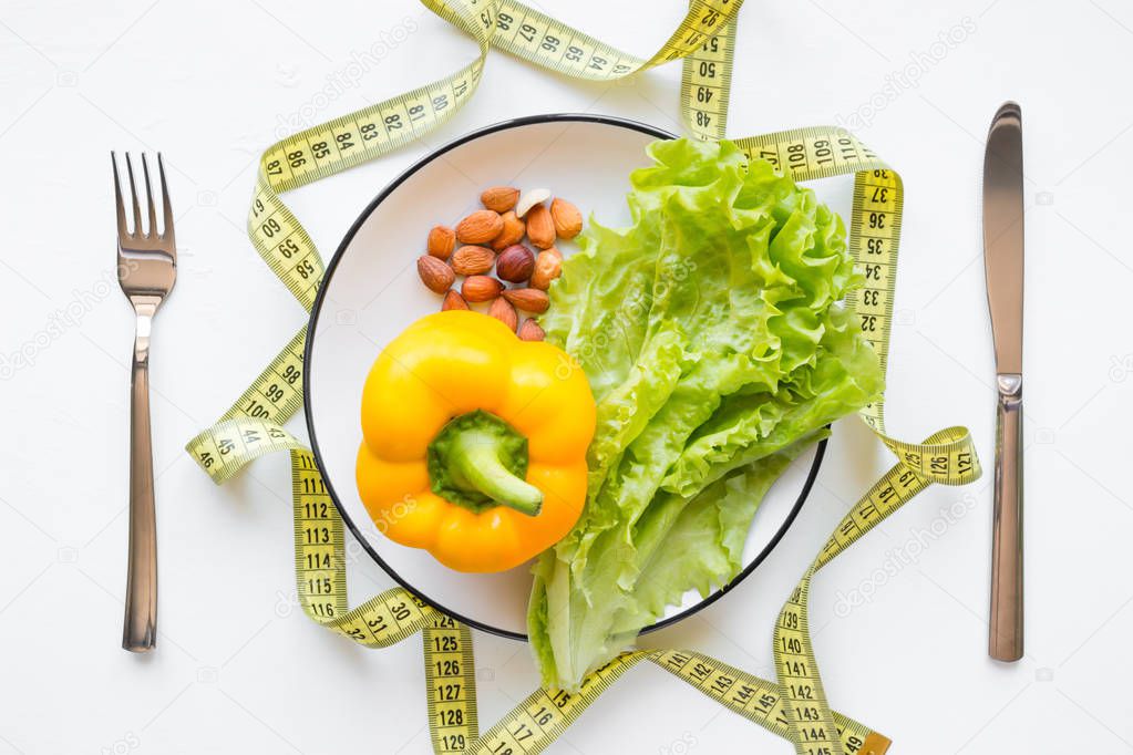 a plate with healthy food and a measuring tape concept diet