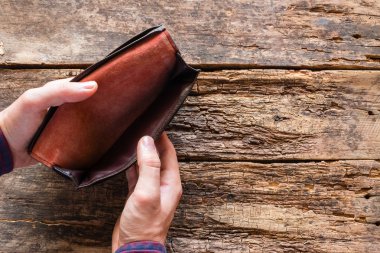 adam boş bir çanta arıyor. para yok. ahşap arka plan üzerinde metin için yer