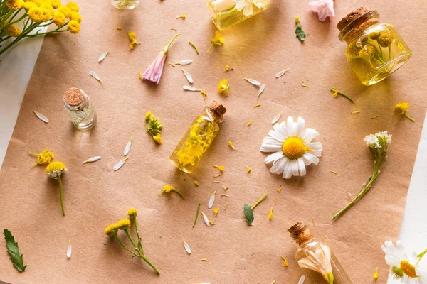 Field flowers and bottles with natural cosmetics on a white background close-up