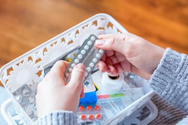 young woman pulls birth control pills