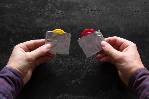 Homem Segurando Preservativos Abertos Amarelos Vermelhos Fundo Preto Conceito Contracepção — Fotografia de Stock