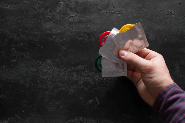 Hombre Sosteniendo Condón Color Sobre Fondo Negro Con Espacio Para —  Fotos de Stock