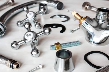 Tesisat - civatalar, contalar, beyaz arka planda parçalanmış su musluğunun parçaları