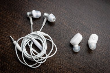Beyaz kablosuz bluetooth kulaklık ve birbirine dolanmış kulaklıklar.